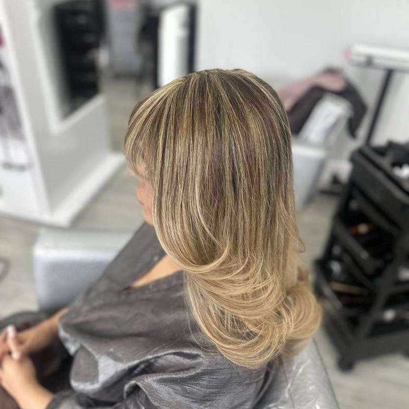 Client with long, blended balayage extensions styled in soft waves